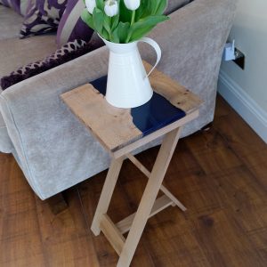 Ash and blue resin side table on tripod legs with vase of flowers
